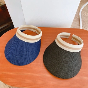 Detail of wide brim straw sun visors in blue and black with elastic striped headbands