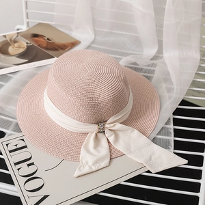 Detailed shot of pink straw hat with white ribbon and sparkling rhinestone buckle