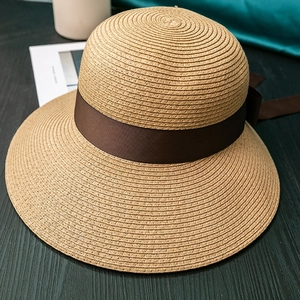 Detailed macro view of woven straw sun hat with elegant brown ribbon and bow decoration