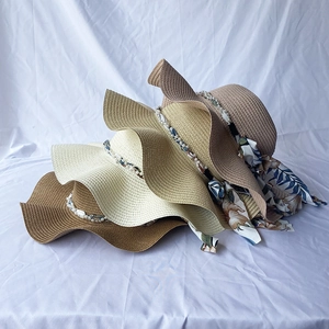 Detail of four colorful wide brim straw hats with pearl beads and floral ribbon ties