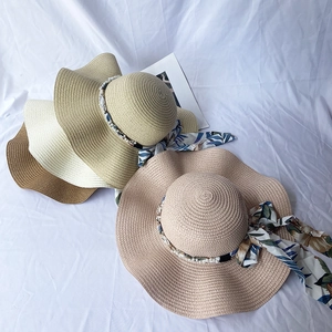 Detail showing wavy wide-brim straw hats with pearl beads and floral ribbon ties