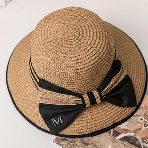 Détail d'un chapeau de paille avec ruban noir et lettre M métallique argentée décorative