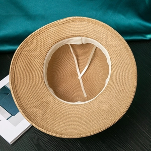 Detail of internal adjustable beige silk ribbons and white sweatband inside straw hat
