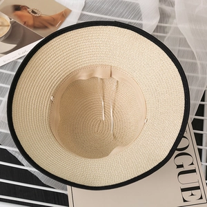 Detail view of large straw sun hat interior with beige woven texture and black fabric brim