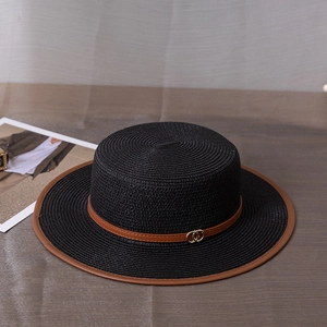 Détail du chapeau de paille noir avec ruban en cuir marron et boucles dorées