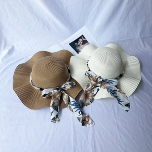 Straw sun hats with wavy brims, floral ribbons, and pearls for beach vacation style