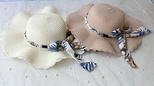 Détail de chapeaux en paille ondulés avec perles et rubans en satin tropicaux