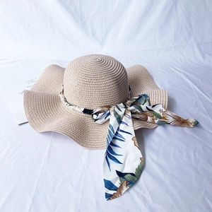 Beige wide brim straw sun hat with floral silk ribbon and wavy edges for beach travel