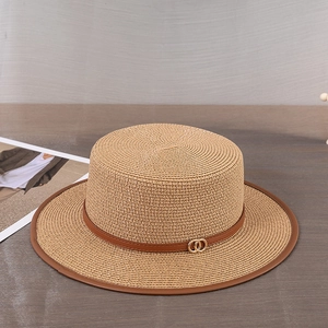Détail d'un chapeau de paille à sommet plat avec ruban en cuir brun et boucle dorée