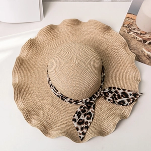 Detail of wide brim straw sun hat with leopard print ribbon and wavy edge texture