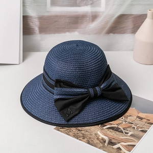 Détail du chapeau de soleil en paille bleu marine avec un grand nœud noir et lettre M