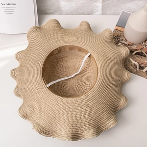 Detail of khaki straw sun hat with scalloped wavy brim and elastic white wind strap