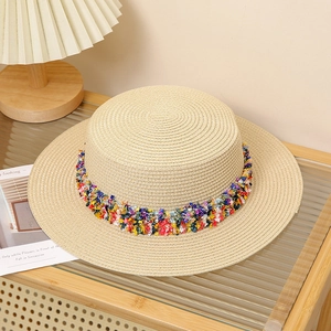 Detail of bohemian flat top straw hat featuring colorful fringe trim and woven texture