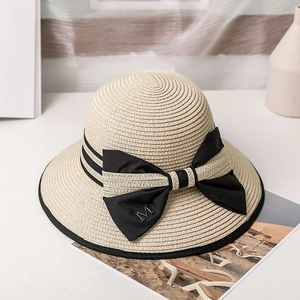 Détails de texture d'un chapeau de paille avec ruban noir et lettre M en métal doré