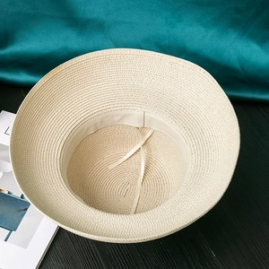 Detail of beige straw sun hat showing interior weaving texture and adjustable chin strap