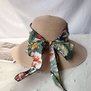 Détail d'un chapeau de paille à larges bords avec ruban floral tropical et nœud élégant
