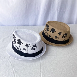 Detail view of khaki and white straw fedoras with black palm tree prints and ribbon