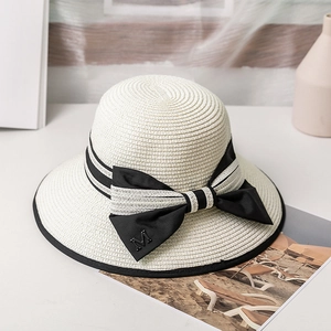 Détail du chapeau de paille tressé avec ruban noir, nœud et breloque lettre M