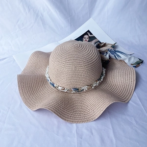 Detailed weave of beige straw sun hat featuring a chic pearl and floral ribbon trim