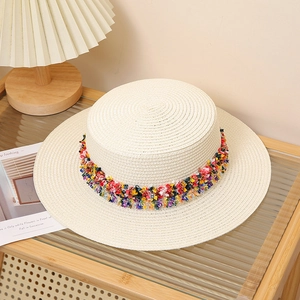 Close-up of beige woven straw hat with colorful pom-pom ribbon on a display stand