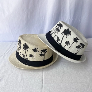 Detail of two woven straw fedora hats with black coconut tree patterns for beach vacations
