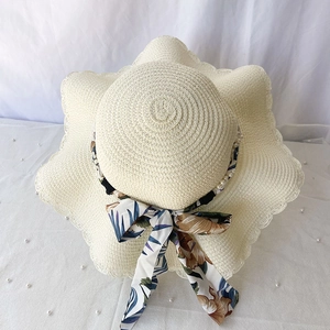 Détail d'un chapeau de paille d'été avec bord festonné ruban fleuri et perles