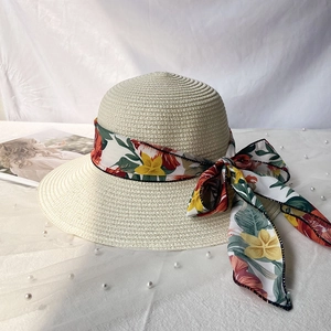 Détail d'un chapeau de paille beige avec ruban floral coloré et nœud élégant
