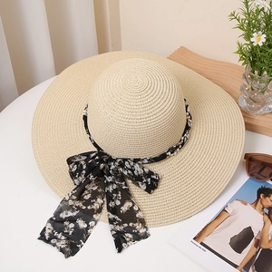 Detail of summer straw hat with floral chiffon ribbon, pearls, and metal chain decoration