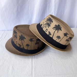 Detailed view of woven fedora hats with coconut tree prints and black ribbon trim