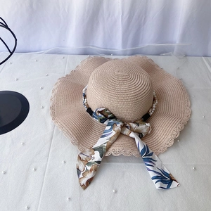 Détail d'un chapeau de paille beige avec bords ondulés, perles et ruban à fleurs