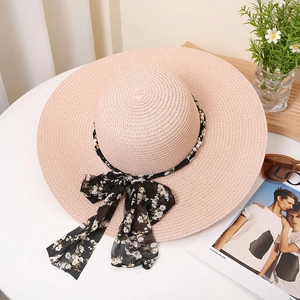 French style straw sun hat with wide brim, floral ribbon and pearl trim on white table