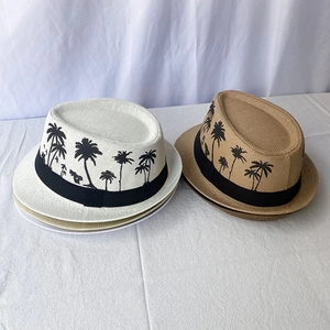 Close-up of woven straw fedora hats with black palm tree patterns and decorative bands