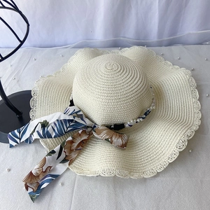Détails d'un chapeau de paille à larges bords avec garniture en perles et ruban en soie