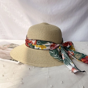 Détail d'un chapeau de paille avec ruban fleuri tropical et un nœud élégant
