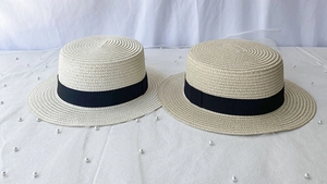 Close-up of flat-top straw boater hats in beige and light coffee with black ribbons