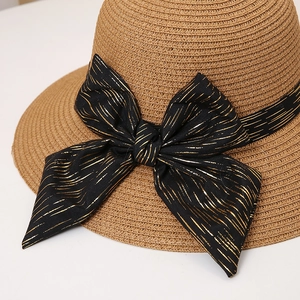 Close-up of a woven straw hat with a large black and gold ribbon bow detail