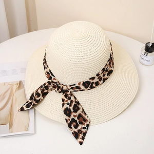Detail of beige wide-brim straw hat featuring a stylish leopard print ribbon bow