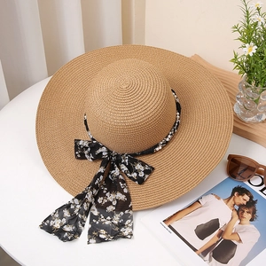 Detail of wide brim straw hat featuring floral ribbon and elegant pearl accents