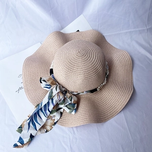 Detail of wide wave brim straw sun hat with floral ribbon and white pearl accents