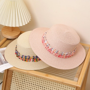 Bohemian style flat top straw hats in pink and beige colors with colorful decorative bands