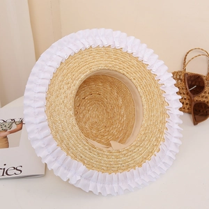Detail view of the elegant white lace trim and woven straw texture on the sun hat