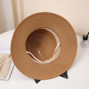 Internal detail of a dark brown straw sun hat with an elastic windproof chin strap