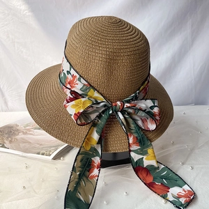 Détail du chapeau de paille d'été avec nœud floral coloré et texture tressée naturelle