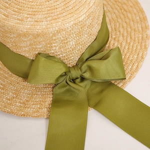 Detail of the olive green ribbon bow and fine straw weave texture on the sun hat