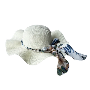 White wide-brim wavy straw hat for women with pearl band and floral ribbon detail
