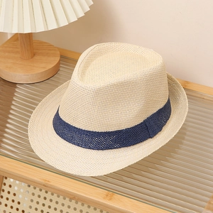 Detail of hand-woven straw panama hat with navy blue band on glass surface