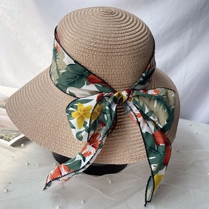 Détail d'un chapeau de paille kaki avec ruban floral et texture de tissage fine