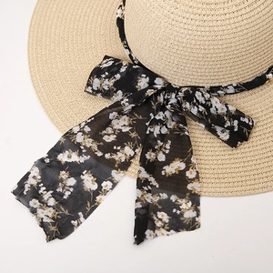 Detail of wide brim straw hat featuring floral chiffon bow with pearl and chain accents