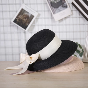 Black and beige straw sun hats with elegant bow ribbons shown in a stylish home setting