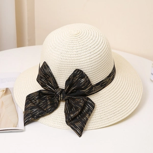 Close-up of beige straw sun hat with black gold-threaded bow decoration and woven texture